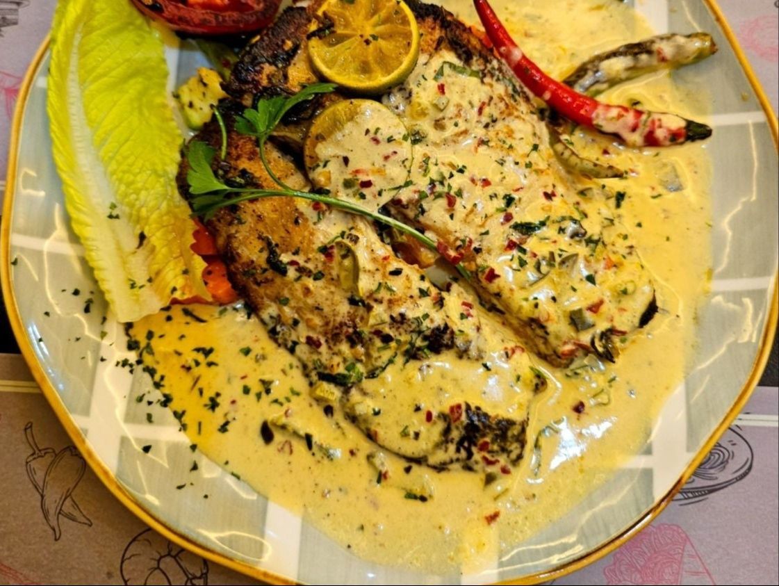 ستيك سمك مشوي at Cock "N" Bull. قطعة سمك سميكة وعصيرية متبلة بمزيج من الأعشاب وزيت الزيتون وقشر الليمون ولمسة من الثوم Pakistani restaurant in Al Majarra, Sharjah, UAE